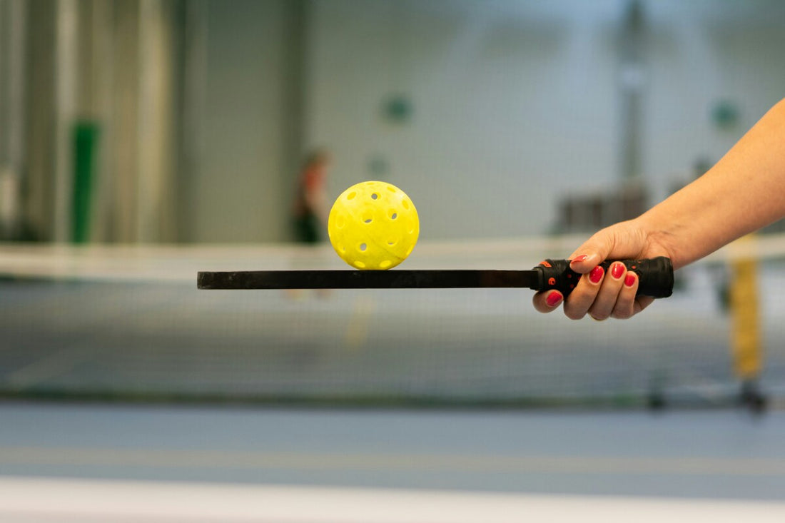 A person holding a premium pickleball paddle with a wiffle ball