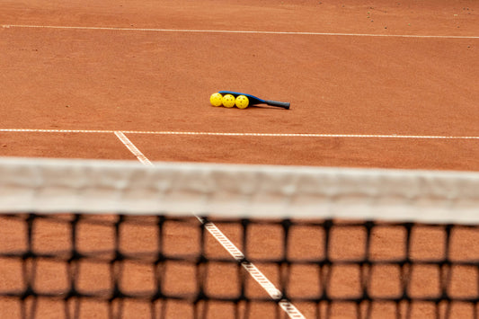 Pickleball paddle and ball resting on the court.